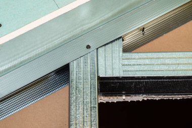Mounted green plasterboards to an aluminum loft frame, visible black screws.