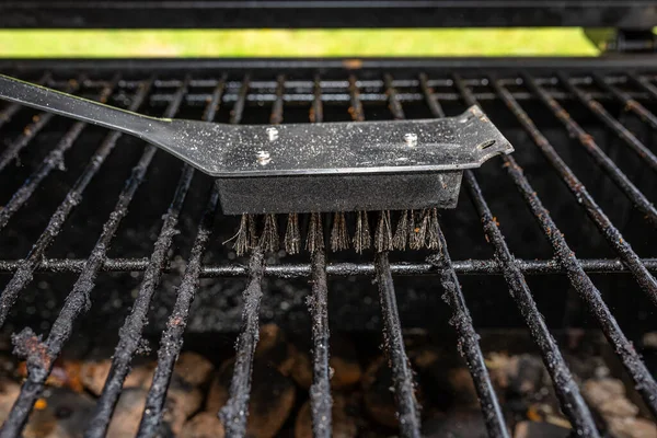Cleaning a dirty grill while standing on the terrace and emptying the ashes.
