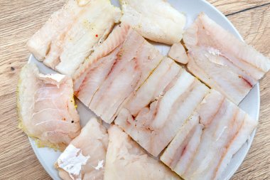 Beyaz bir tabakta karelere ayrılmış taze bir balık filetosu..