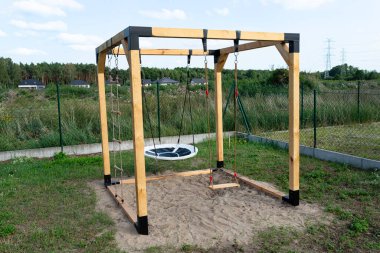 A modern cube playground made of wood and metal corners, standing in the yard behind the house.