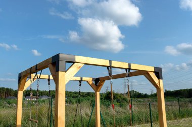 A modern cube playground made of wood and metal corners, standing in the yard behind the house.