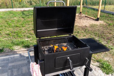 Lighting a home grill with charcoal and white kindling for the grill, standing in the home garden, using a barbecue lighter.