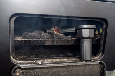 Lighting a home grill with a battery blower, standing in the backyard.