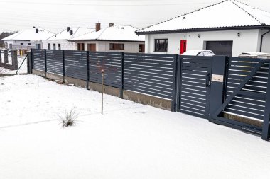 Antrasit renginde modern panel çitleri, görünür sürgülü kapı ve kale kışın posta kutusu ile..