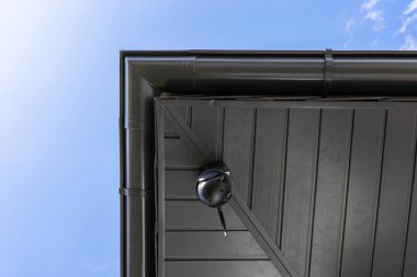 Yuvarlak kablosuz kamera çatının köşesine monte edilmiş, tek bir aile evini izliyor..