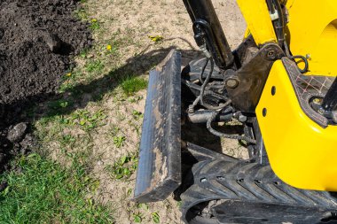 Mini kazıcı çit boyunca kanalizasyon borularına kadar bir çukur kazıyor..