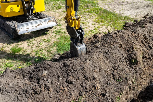 小型挖掘机沿着篱笆在花园里挖一个洞 一直通到排水管 — 图库照片