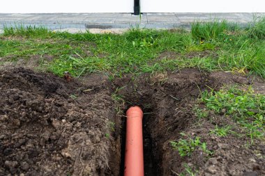 Toprağa gömülü turuncu PVC boru kanalizasyon borusuna bağlanmak için kullanılmış..