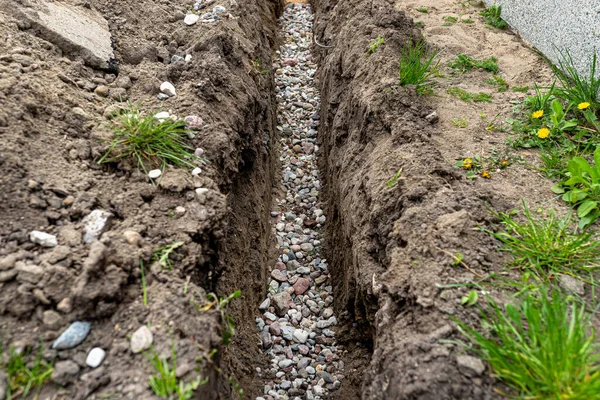 壕沟沿着栅栏在院子里挖的一条壕沟 用来铺排水管 用可见的砾石 — 图库照片