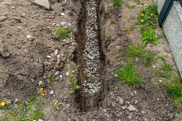 壕沟沿着栅栏在院子里挖的一条壕沟 用来铺排水管 用可见的砾石 — 图库照片