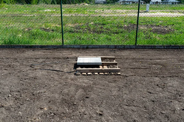 在院子里用一个用混凝土立方体压住的托盘围住切诺兹 准备播种草坪 — 图库照片