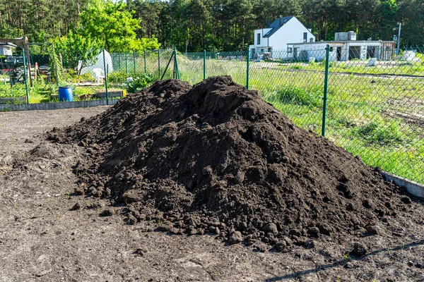 一堆纯净的黑土躺在篱笆旁边的院子里 — 图库照片