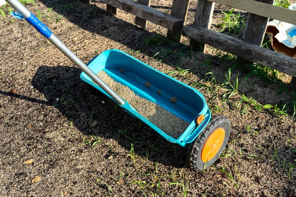 stock image Sowing grass with a wheeled seeder, visible grass grains and black soil.