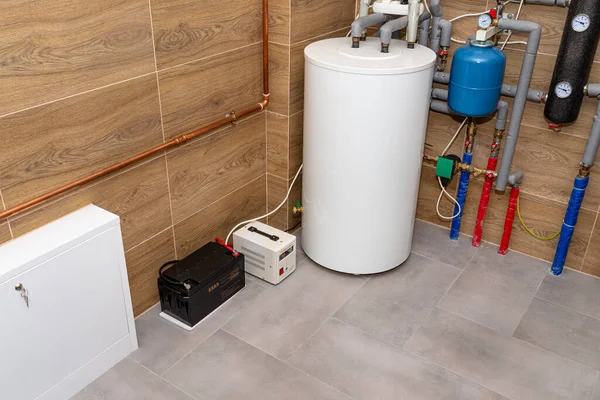 Modern gas boiler room lined with ceramic tiles imitating wood, visible emergency power supply with a 12 volt battery.