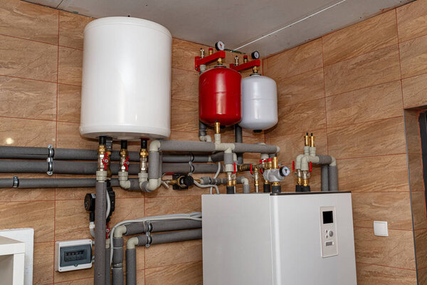 A modern air heat pump installed in the home's boiler room, visible plastic pipes and valves.