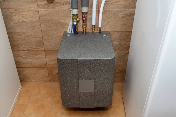 A modern air heat pump installed in the home's boiler room, visible heat exchanger.