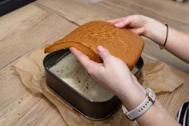 Polonya pastası hazırlama, kremalı şekerleme, kadın bir kat pasta koyar.