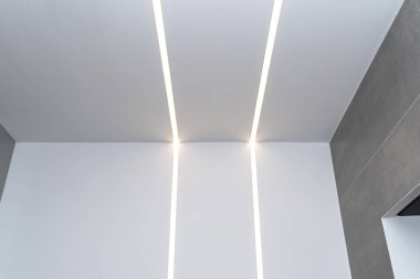 LED ışık şeritleri modern bir banyonun duvarına ve tavanına monte edilmiştir..