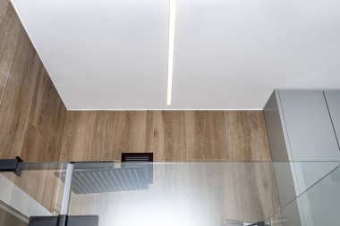LED ışık şeritleri modern bir banyonun duvarına monte edilmiş, görünür bir duş..