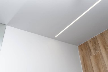 LED ışık şeritleri modern bir banyonun duvarına ve tavanına monte edilmiştir..