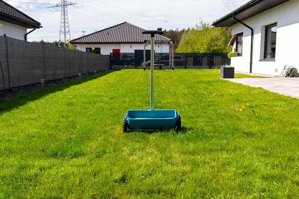 stock image Fertilizing a young lawn with grass fertilizer in granules using a manual grass seeder.