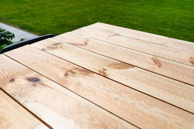 Çiğ ahşaptan yapılmış, bahçe terasında duran vernikle kaplı modern bir masa..