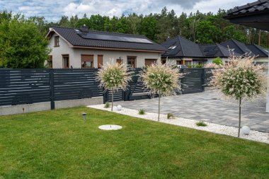 Antrasit renginde modern bir çit garaja açılan görünür bir sürgülü kapı ve posta kutusu olan bir kale..