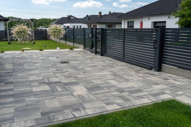 Antrasit renginde modern bir çit garaja açılan görünür bir sürgülü kapı ve posta kutusu olan bir kale..