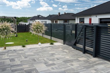 Antrasit renginde modern bir çit garaja açılan görünür bir sürgülü kapı ve posta kutusu olan bir kale..