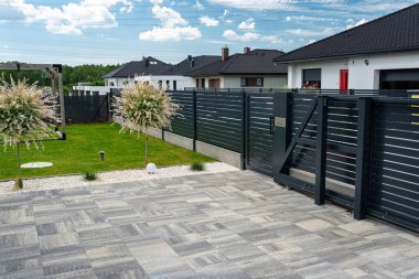 Antrasit renginde modern bir çit garaja açılan görünür bir sürgülü kapı ve posta kutusu olan bir kale..