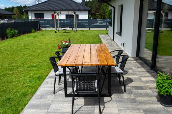 stock image A modern table made of raw wood covered with yacht varnish, standing on the garden terrace.