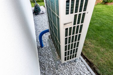 Two efficient outdoor heat pump units placed in front of the house. clipart