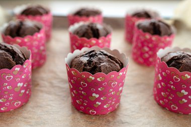 Kahverengi çikolatalı kekler, fırında pişmiş beyaz kağıtlara sarılıp pişirme kağıdının üzerinde yatıyorlar..