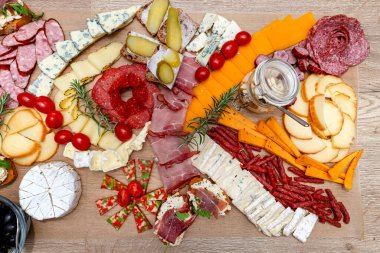 Çeşitli peynirler ve salamlar masaya yayıldı. Yemek kağıdı, evde akşam partisi, üst manzara..