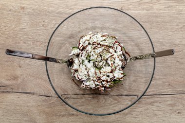 Sebze salatası, beyaz peynir ve salatalıklar masada cam bir kasede..