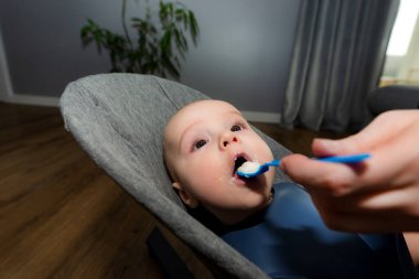 Bir anne plastik kaşıkla bebeğini irmikle besler..