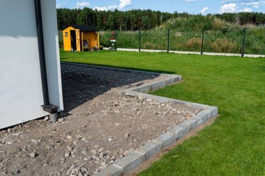 Compacting rubble on a terrace under construction using a gasoline powered hand held compactor. clipart