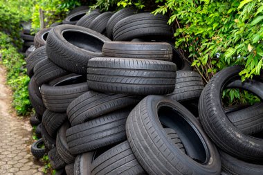 Bir araba tamirhanesinin yanında duran eski ve hasarlı lastikler yığını..