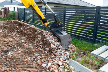 Bir kepçe doldurucu toprak yolu düzleştirmek için teleskopik bir kovayla moloz topluyor..