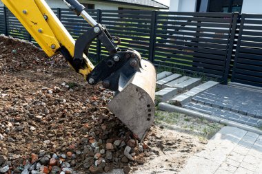 Bir kepçe doldurucu toprak yolu düzleştirmek için teleskopik bir kovayla moloz topluyor..