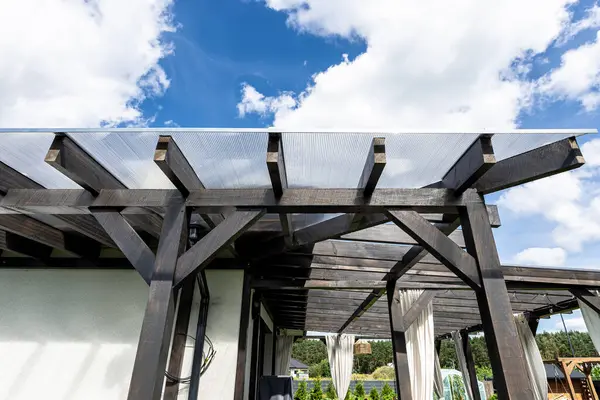 Evin arkasındaki terasın görünür kiriş bağlantıları var. Çatı polikarbonatla kaplı..