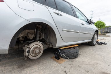 Kışlık lastiklerle değiştireceğim, evin önünde, makas krikosuyla yükseltilmiş bir araba..
