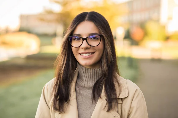 Close-up portrait of independent woman student 20s with amazing smile wearing glasses in the street.