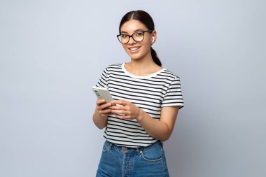 Öğrenmek için telefon ve kulaklık kullanan güzel bir öğrencinin portresi. Teknolojiyle gelişiyor.