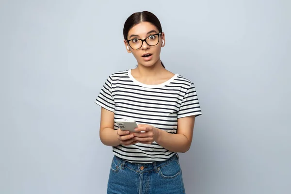 Posible Mujer Sorprendida Estudiante Gafas Sosteniendo Teléfono Inteligente Mirando Recto — Foto de Stock