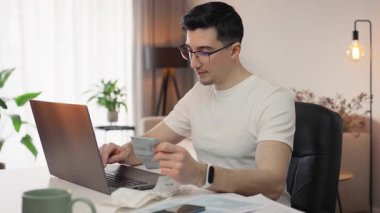 Gözlüklü neşeli bir adam harcamalarını gözden geçirir. Vergilerini öderken gülümseyerek çekleri gözden geçirir. Kendinden emin ve kontrollü, finansmanı kolaylıkla ve olumlu bir şekilde yönetiyor..