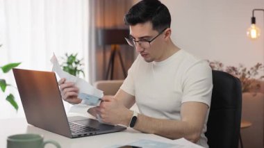 Gözlüklü sinirli adam çekleri havaya fırlatıyor, vergi hesaplamalarıyla bunalmış bir halde. Harcamaları ve evrak işlerini halletmek için çabalarken stres ve kaos devreye giriyor..