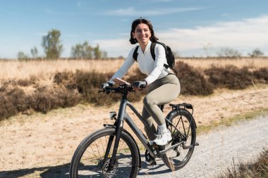Havadar giysiler içinde gülümseyen bir kadın olarak esintili bir yolculuk güneşli bir günde pedal çeviriyor, sağlığın ve özgürlüğün ruhunu yakalıyor..