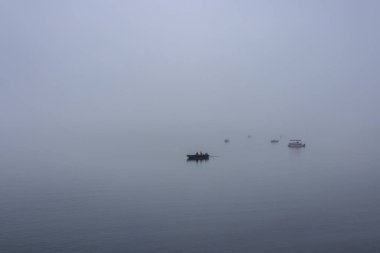 Boats floating in a bay with fog
