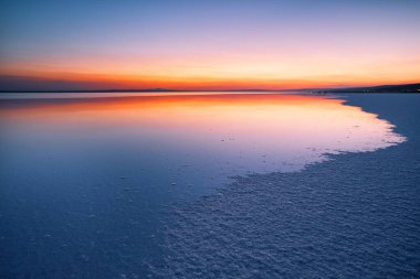 Lake with the smooth water and sky reflection at sunset